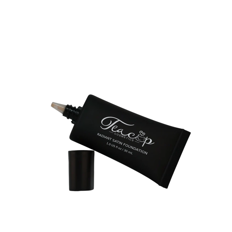 Teacup Cosmetics Radiant Satin Foundation, leaning squeeze tube resting on its cap with silver labeling